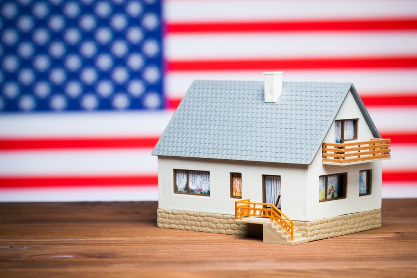 Model domu s pozadím americké vlajky.